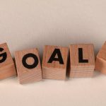 Aligned wooden blocks spelling 'Goals' symbolize target achievement and ambition.